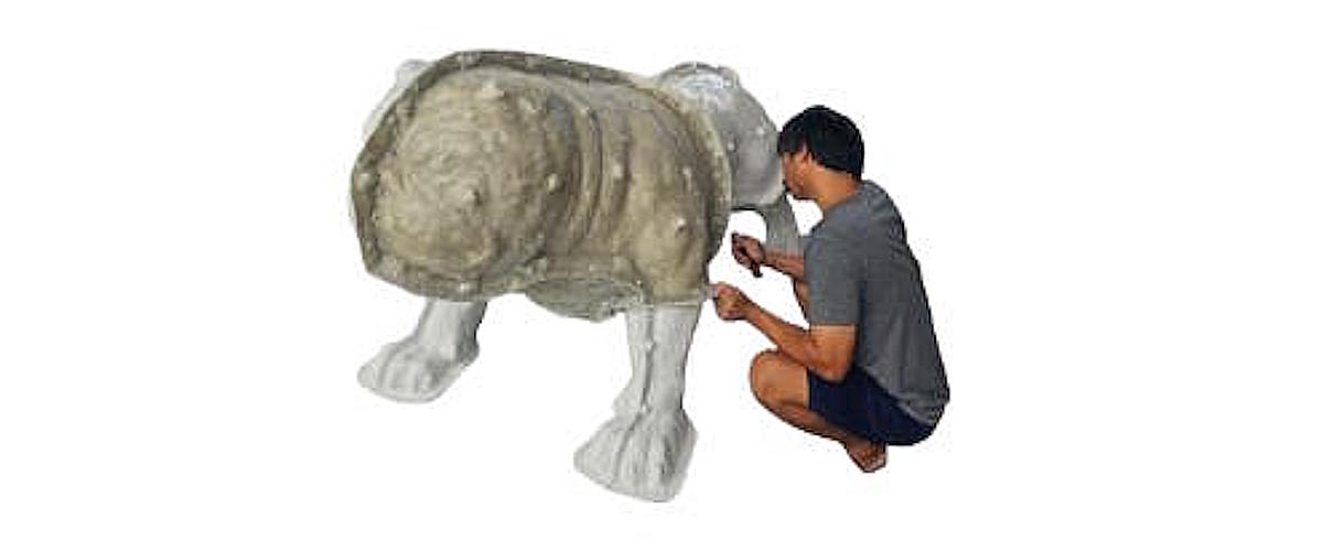 Artist shaping clay on the Tracy High School bulldog mascot sculpture