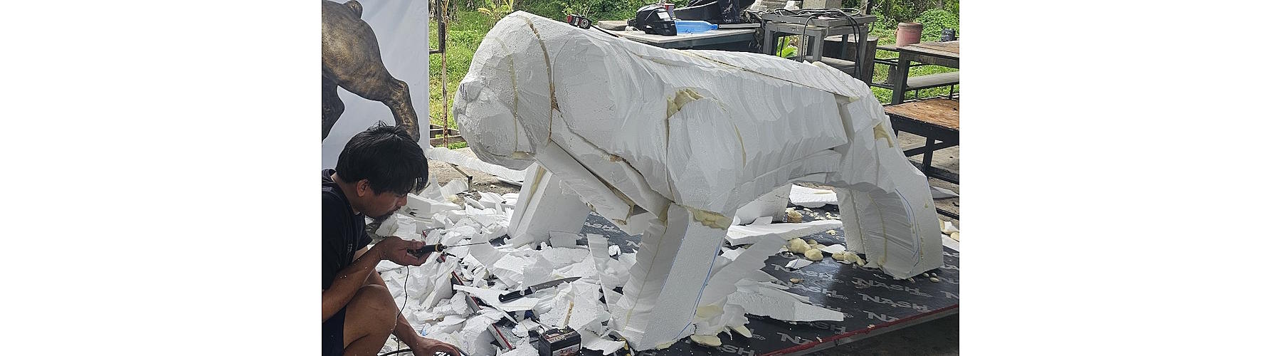 Artist refining the carved foam body of the Tracy High School bulldog sculpture